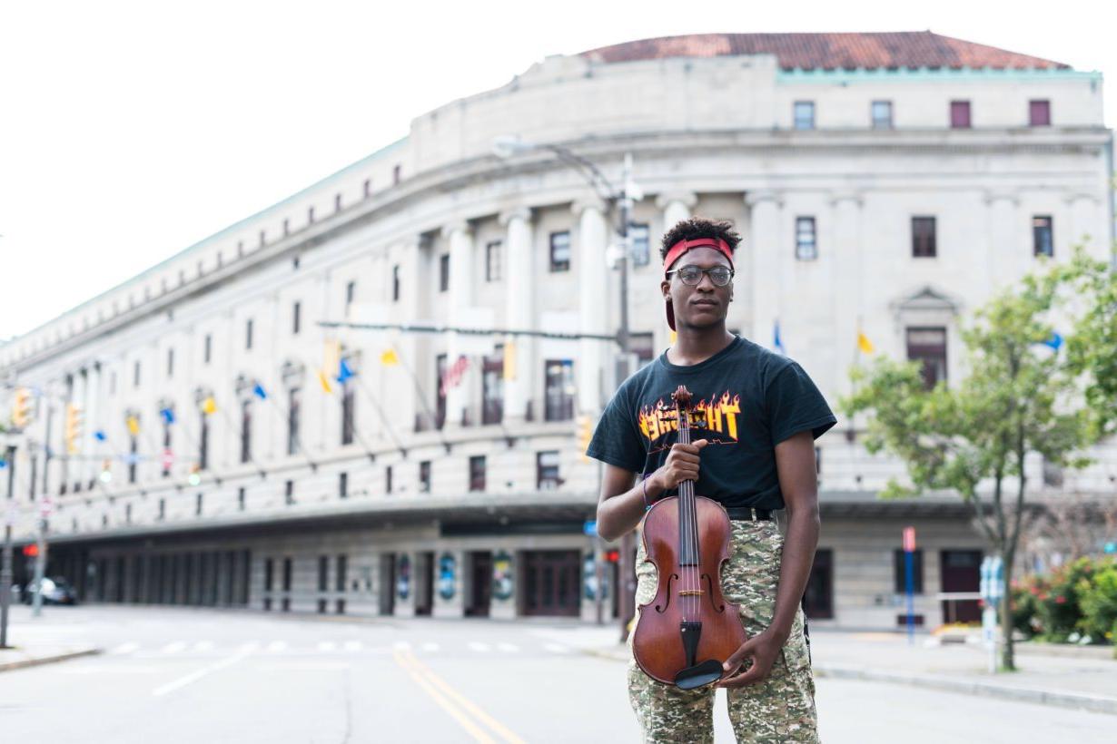 University of Rochester Eastman School of Music student holding a viola outside of Kodak Hall in Rochester