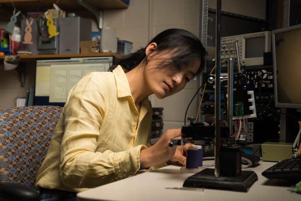 University of Rochester Ph.D. candidate working on a piece of machinery at a desk