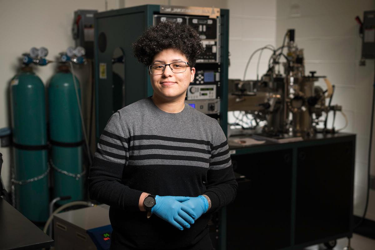 University of Rocheste student in a lab wearing gloves in front of a piece of lab equipment